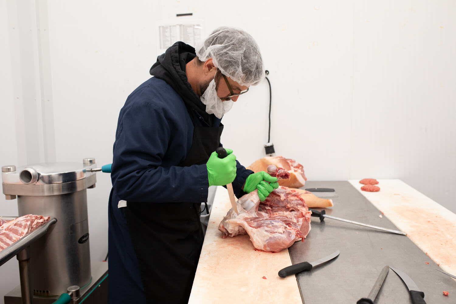 Butcher preparing meat with a knife on a cutting table.